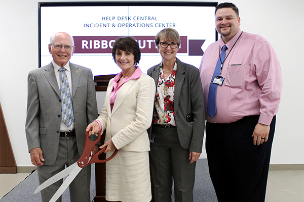 Division of IT executives hold large, ceremonial scissors.